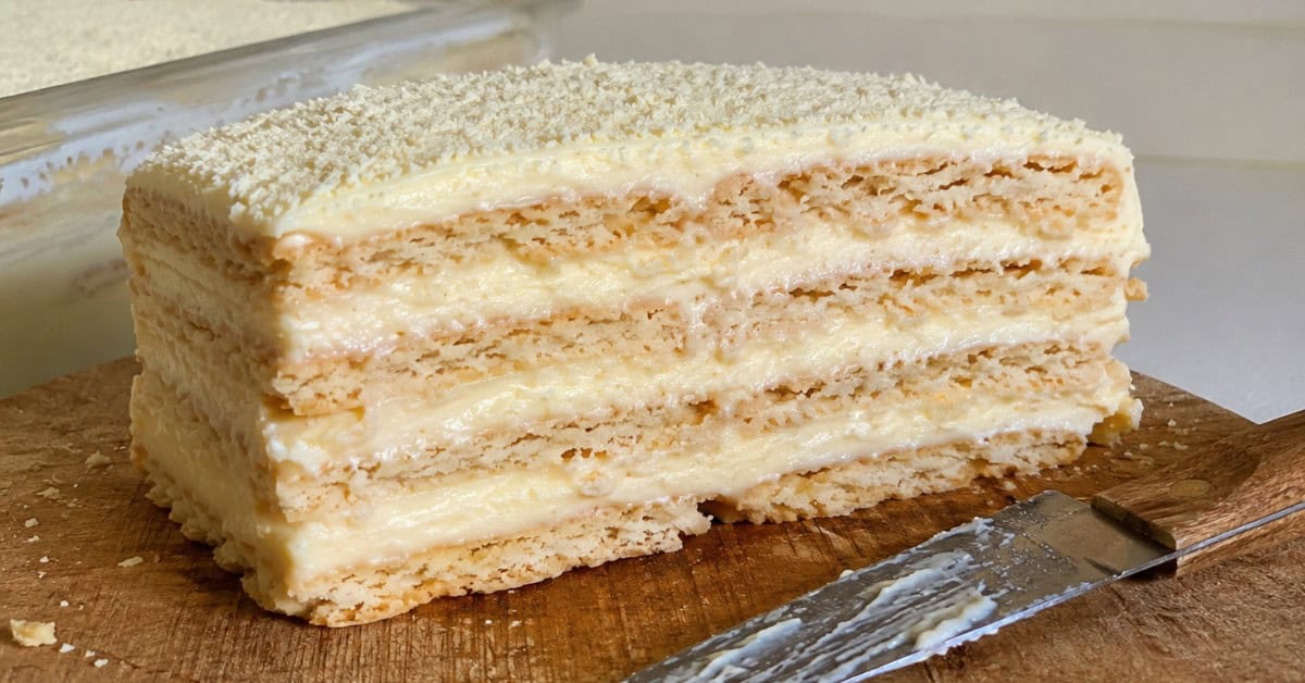 Fatia perfeita de torta alemã de leite ninho cortada em tábua de madeira mostrando as camadas