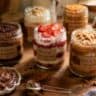 Vendendo Bolo de Pote artesanal com diferentes sabores sobre bancada de madeira rústica em cozinha caseira