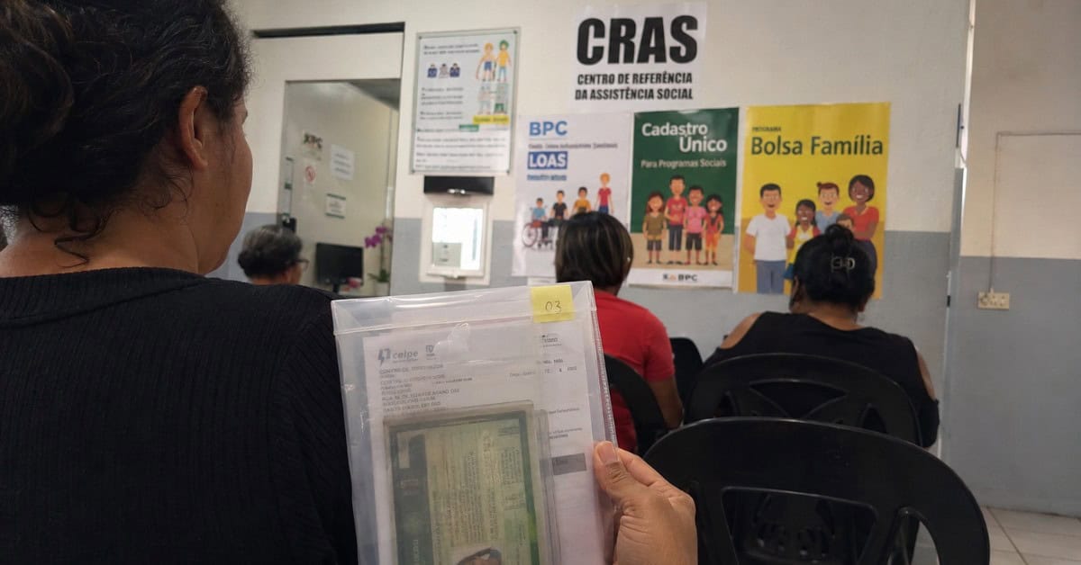 Mulher de costas na fila do CRAS segurando pasta transparente com documentos pessoais como RG e comprovante de residência para cadastro no CadÚnico