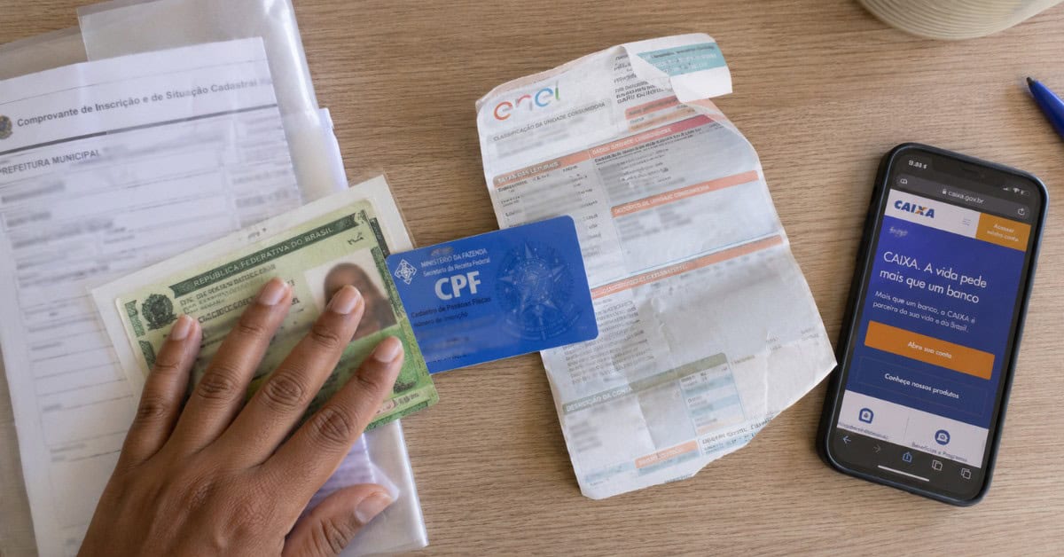 Documentos espalhados na mesa para inscrição no Minha Casa Minha Vida, incluindo RG, CPF e comprovante de residência