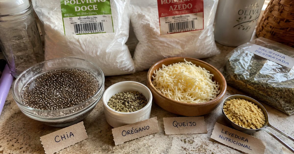 Pequenas tigelas com ingredientes substitutos para biscoito de polvilho como chia, ervas e levedo de cerveja organizados em bancada